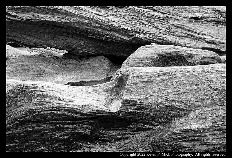 BW photograph of striations worn into rocks by running water.